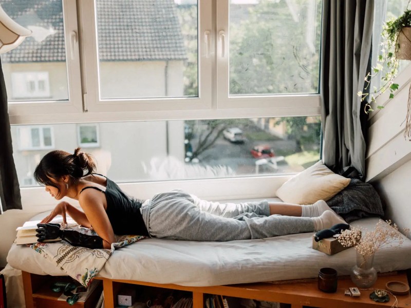 Teenagermädchen liegt am Tag auf ihrem Bett und liest.