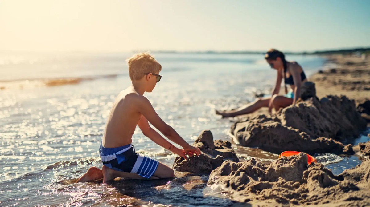 Kinder buddeln mit untergehender Sonne am Strand.
