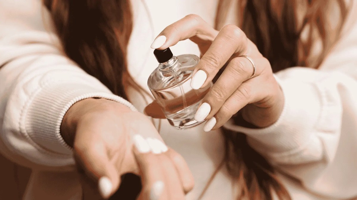 Frau trägt Parfum auf Handgelenk auf.