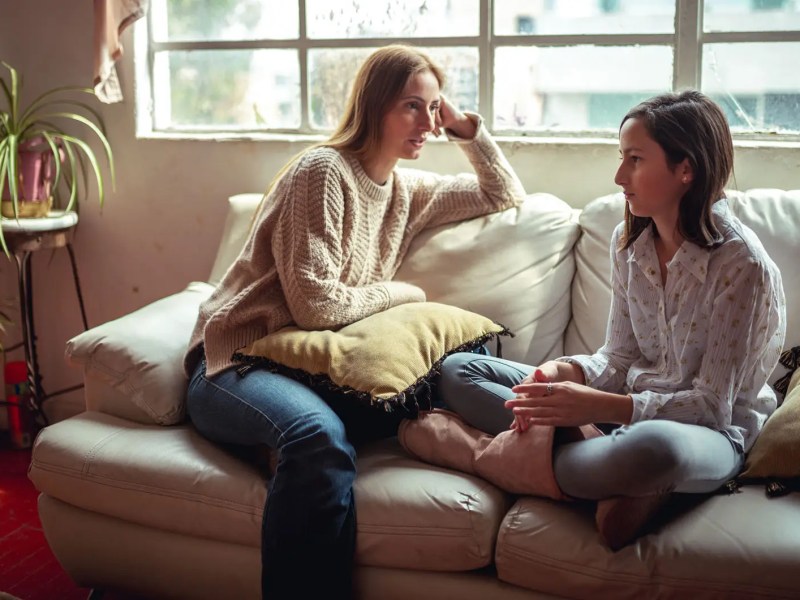 Mutter und Tochter bei einem ernsten Gespräch, beide sitzen auf der Couch.
