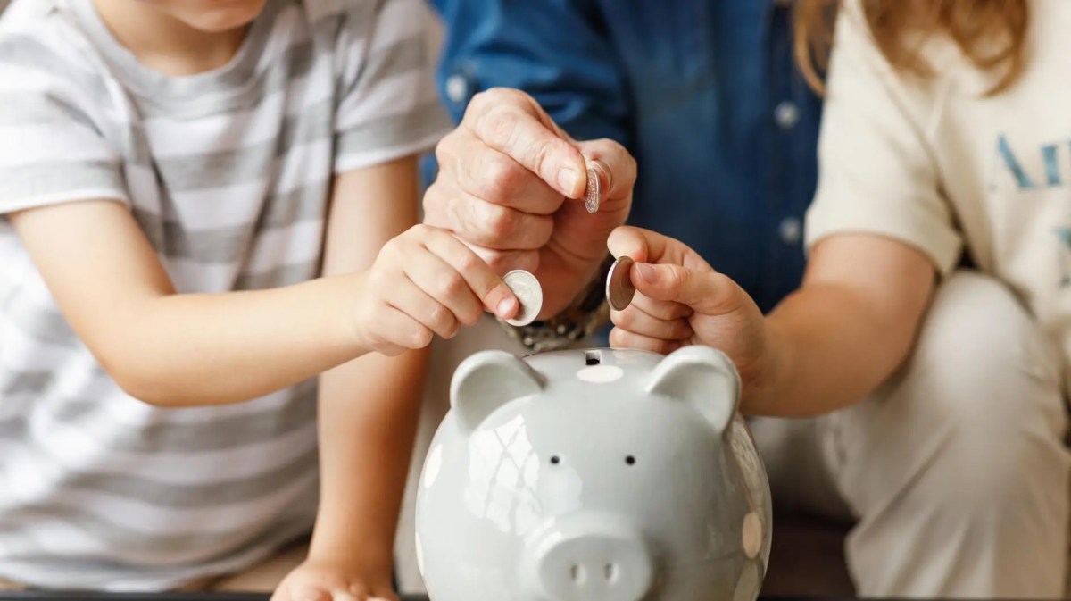 Mann und zwei Kinder werfen Geld in ein Sparschwein.