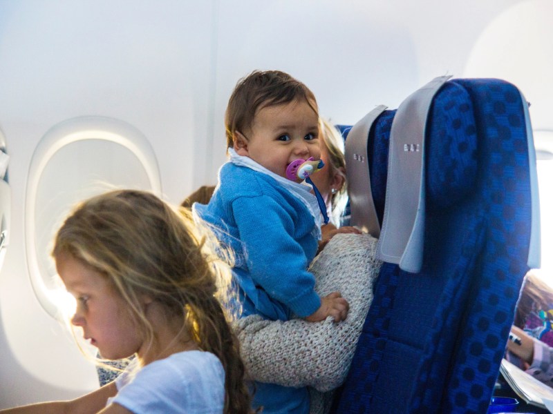 Mutter mit zwei Kleinkindern sitzen im Flugzeug