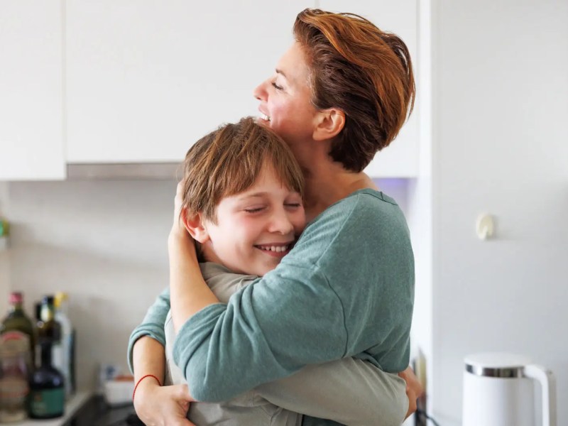 Mutter und Sohn umarmen sich in der K&uuml;che.