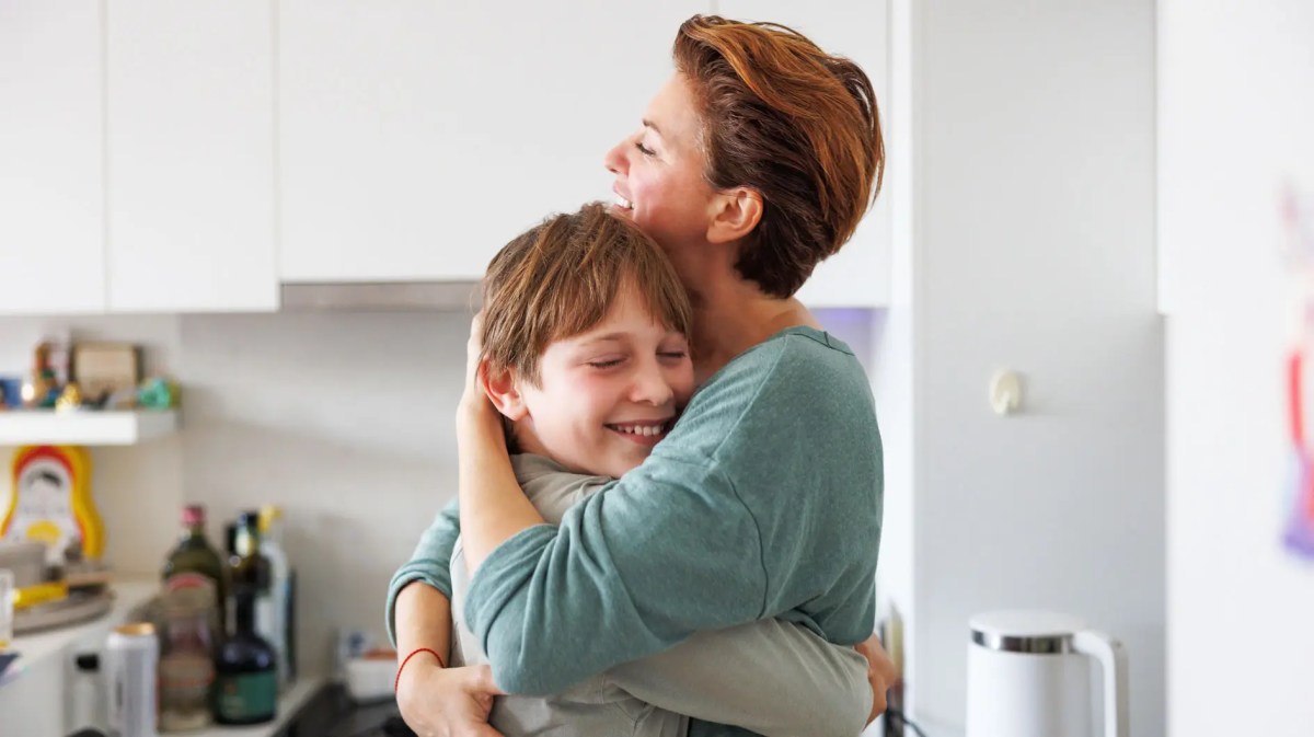 Mutter und Sohn umarmen sich in der Küche.
