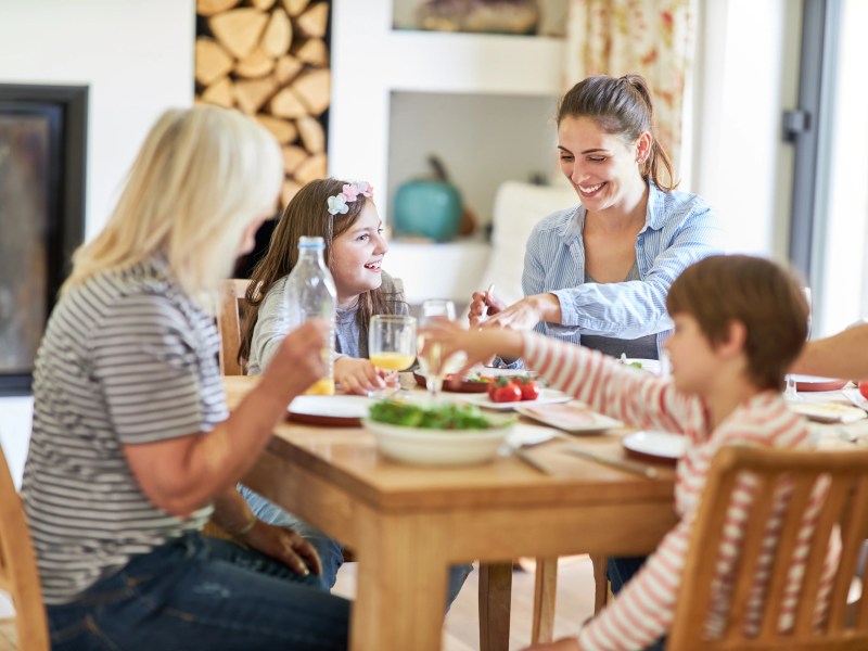 Mutter mit Sohn, Tochter und Oma beim Mittagessen am Tisch.