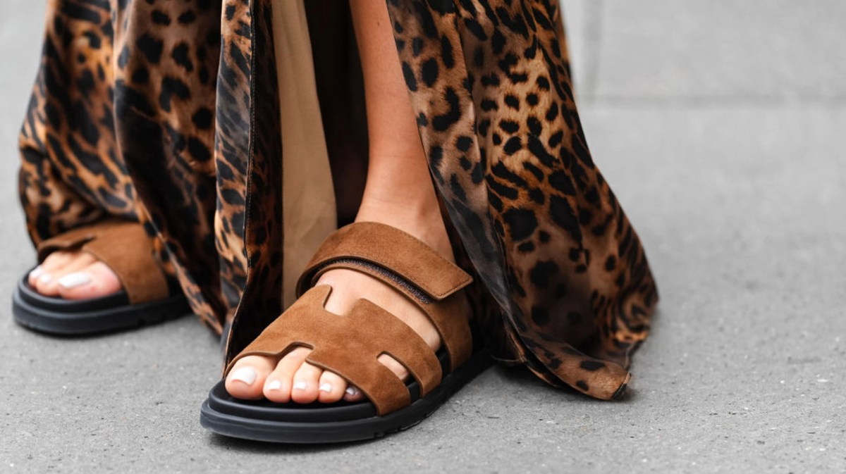 Frau mit braunen Sandalen und langem braunen Kleid